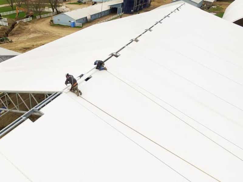 Workers building a fabric roof for a custom riding arena.