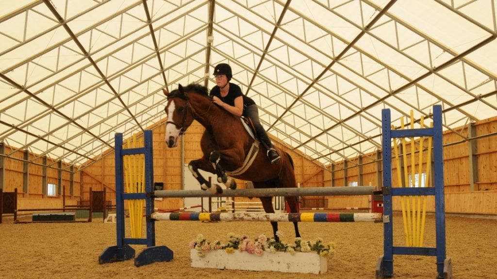 Horse jumping in fabric roof riding arena in Bolton, ON.