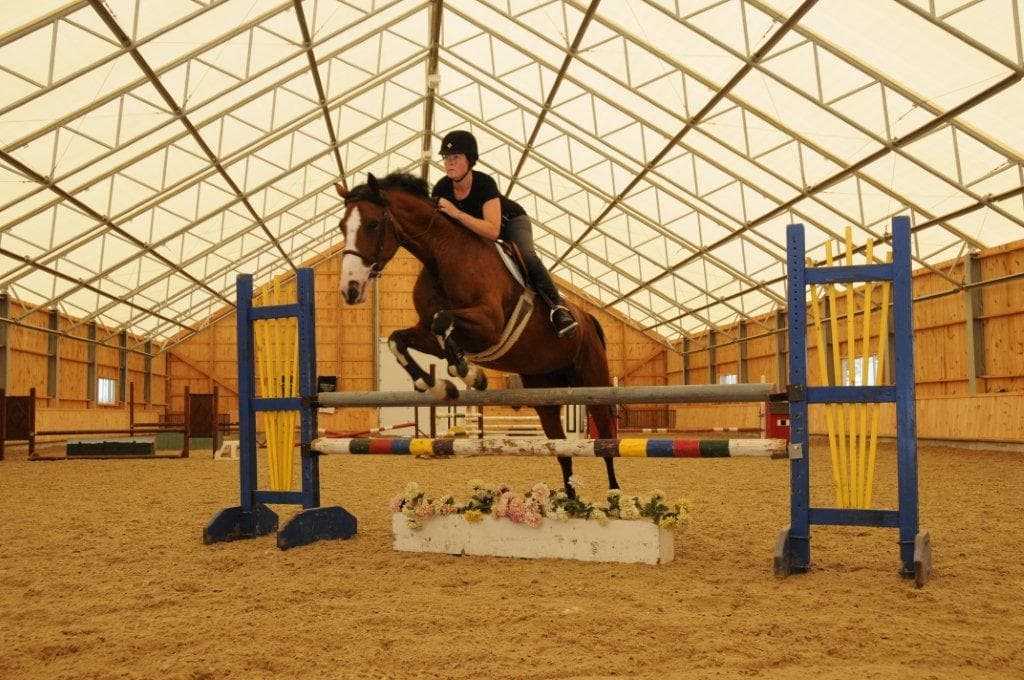 Horse jumping in fabric roof riding arena in Bolton, ON.